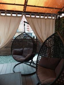 2 sillas sentadas en un porche con cortinas en Rooms Apartments en Samara