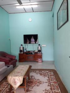 a living room with a couch and a tv at Homestay Ustaz in Taiping