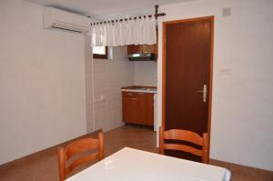 eine Küche mit einem Tisch, Stühlen und einer Tür in der Unterkunft Holiday Home Garina in Draga Bašćanska