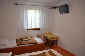 a small room with two beds and a television at Holiday Home Garina in Draga Bašćanska