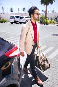Un uomo in giacca e cravatta che passa davanti a un'auto di MIA HOTELS Fes a Fes