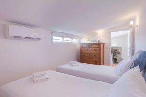 - une chambre blanche avec 2 lits et une commode dans l'établissement LovelyStay - Bairro Alto Terrace Wonder, à Lisbonne