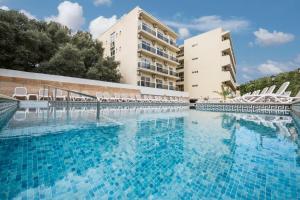 a large swimming pool with chairs in front of a building at azuLine Hotel Bahamas y Bahamas II in El Arenal