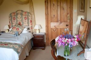 a bedroom with a bed and a vase of flowers on a table at Lullington House in Frome