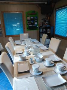 une table avec des tasses et des soucoupes blanches dans l'établissement Vila Paula & SPA -ALL INCLUSIVE, à Sovata