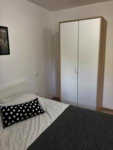 a bed with a black and white pillow and a closet at Small & Sweet Apartments in Belgrade
