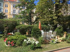 un jardín con sombrilla, sillas y flores en Pension Jana - Domov Mládeže, en Praga