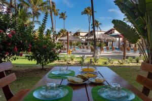 une table en bois avec des assiettes de nourriture dessus dans l'établissement Apartamento no Taiba Beach Resort, à Taíba