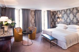 um quarto com uma cama, uma mesa e cadeiras em Hôtel du Danube Saint Germain em Paris