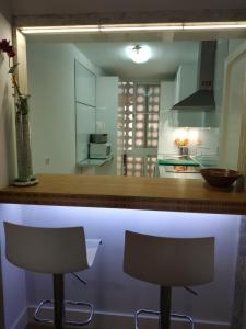 a kitchen with two bar stools at a counter at Kiana Mirador Fuentebravía in El Puerto de Santa María