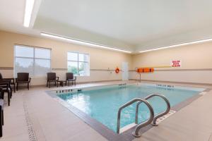 una piscina en una habitación con sillas y mesa en Comfort Inn & Suites, en Bowmanville