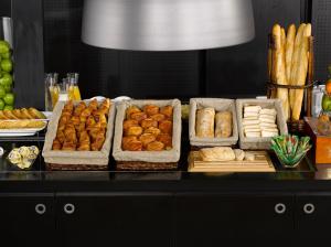 a buffet with several trays of pastries and bread at Campanile Saint-Etienne Est- Saint-Chamond in Saint-Chamond