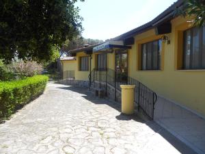 a yellow house with a sidewalk next to a building at Hotel Fortezza in Arborea