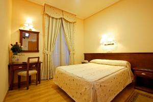 a bedroom with a bed and a table and a mirror at Hostal Silserranos in Madrid