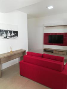 sala de estar con sofá rojo y TV de pantalla plana en Flats Dunas Cabo Frio, en Cabo Frío