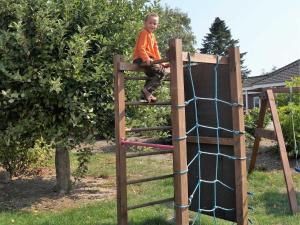 a young boy sitting on top of a wooden play structure at Ferienhof Andreas Hansen in Rettin