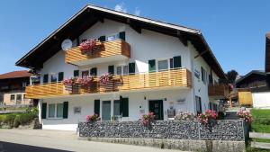 ein weißes Haus mit Holzbalkonen und Blumen in der Unterkunft Ferienhaus Linder in Fischen im Allgäu