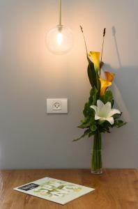 a vase of flowers on a table with a light at The Roof - By Sea Land Suites in Tel Aviv