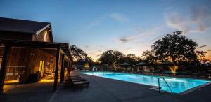 a swimming pool with tables and chairs next to a building at Sun Outdoors Paso Robles in Paso Robles