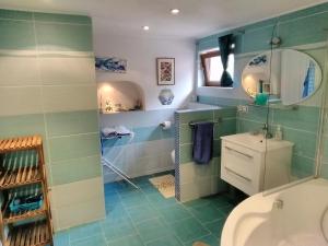 a bathroom with green tiles and a toilet and a sink at Sophia Cozy Self Catering Apartment in Dolní Břežany