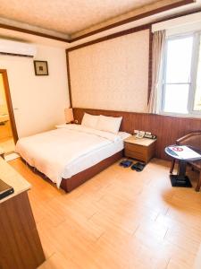 Un dormitorio con una cama y una mesa. en 玉泉旅館 en Jiaoxi