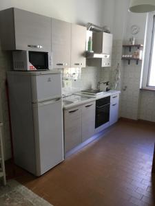 una cucina con armadi bianchi, lavandino e piano cottura di Appartamento - Casa vacanza Nonna Grazia a Roma