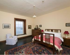 a bedroom with a bed and a chair and a window at Blackhead Lighkeeper's Houses, Antrim in Whitehead