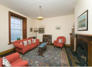 a living room with two red chairs and a fireplace at Blackhead Lighkeeper's Houses, Antrim in Whitehead