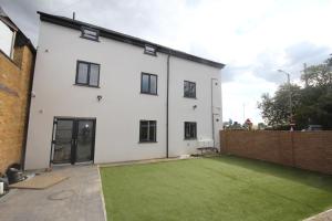 a white house with a green lawn in front of it at Holden Court Apartments - Apt 3 in West Drayton