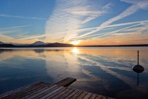 a sunset on a lake with a wooden dock at Gubelhof Suites in Zug
