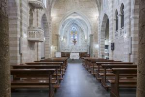 uma igreja com fileiras de bancos de madeira em Monastero Santa Chiara Guest House em Oristano