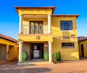 ein gelbes Haus mit einer Veranda und einem Balkon in der Unterkunft Hlulani Guest House in Northam