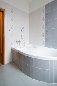 a bath tub in a bathroom with gray tiles at Lipovka penzion in Hodonín