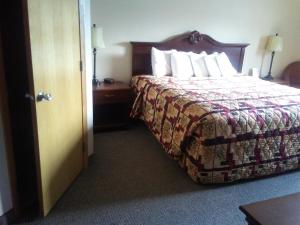 a hotel room with a bed and a door at Knights Inn and Suites - Grand Forks in Grand Forks