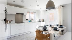 una cocina con armarios blancos y una mesa con sillas. en Heath Reach en Poole