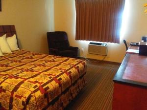 ein Hotelzimmer mit einem Bett und einem Stuhl in der Unterkunft Knights Inn and Suites - Grand Forks in Grand Forks