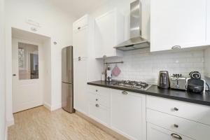 een keuken met witte kasten en een roestvrijstalen koelkast bij Lovatelli Home al Campidoglio in Rome +25 foto's