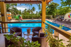 una piscina con sillas y una mesa junto a un complejo en Floral Inn Family, en Porto Seguro