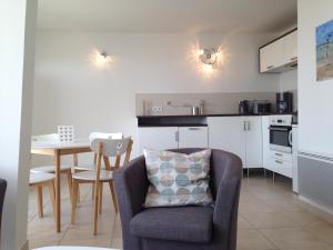a living room with a chair and a table in a kitchen at Joussac Côté Plage - Devant l'océan in Soulac-sur-Mer