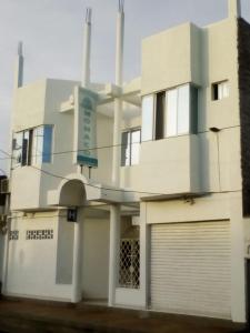 a white building with a garage in front of it at Hotel Monaco De Riohacha in Ríohacha
