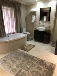a bathroom with a tub and a toilet and a sink at Annie's Place in Kempton Park