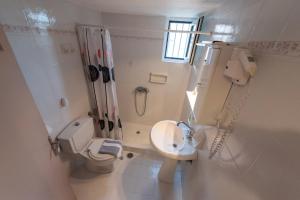 a white bathroom with a toilet and a sink at Villa Tasos Koutsoubos in Koroni