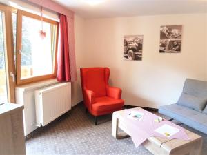 a living room with a red chair and a table at Alpina Appartements in Haldensee