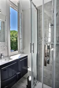 a bathroom with a shower and a sink and a window at Les Terrasses du parc Cordier in Trouville-sur-Mer