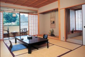 ein Wohnzimmer mit einem Tisch, Stühlen und Fenstern in der Unterkunft Kadonobo Ryokan in Kōbe