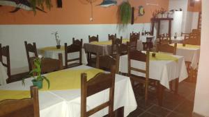 a dining room with tables and chairs with white tablecloths at Pousada Brilho do Sol in Guarujá