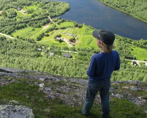 a person standing on top of a mountain looking at a lake at Cabin Huskyfarm Innset in Innset