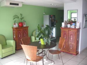 uma sala de jantar com uma mesa e cadeiras e paredes verdes em HOME DU BUISSON Hôtel des Familles em Isle