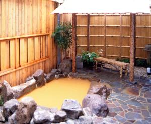 un estanque en un jardín con un banco y algunas rocas en Kadonobo Ryokan, en Kobe