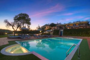 a swimming pool in a yard with chairs and umbrellas at Villa Gens Camuria in Camerano